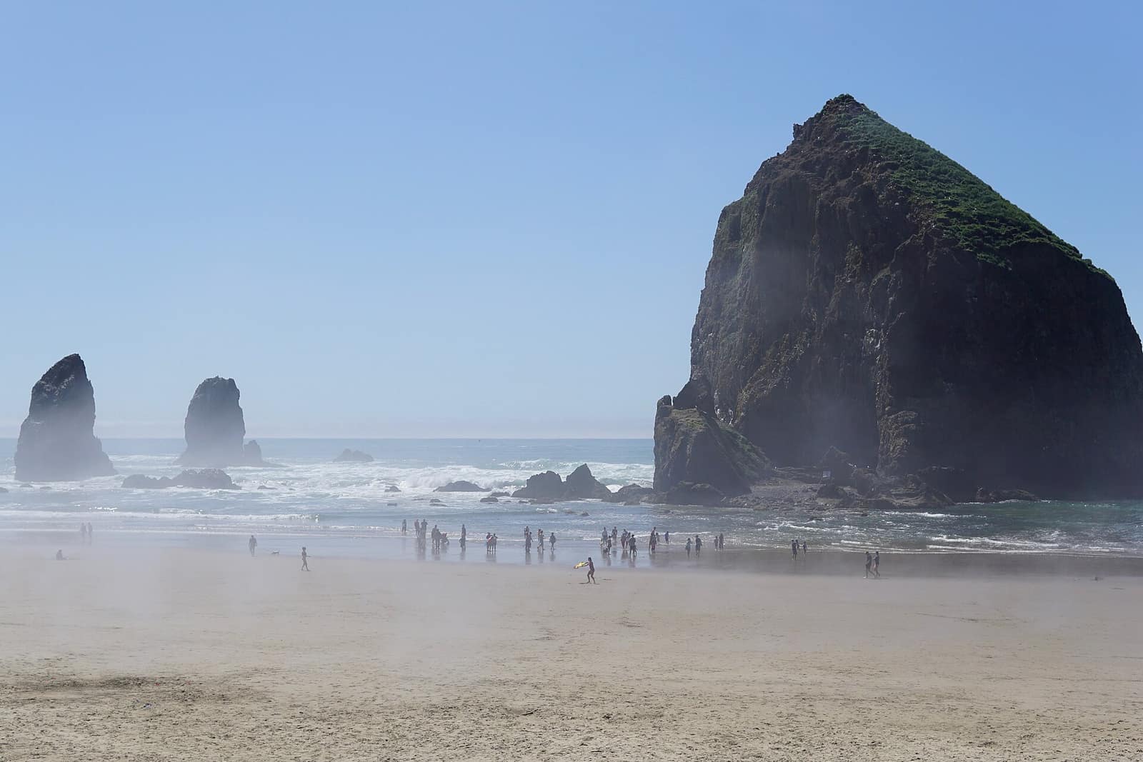 Haystack Rock and the Needles in light morning fog with beachgoers