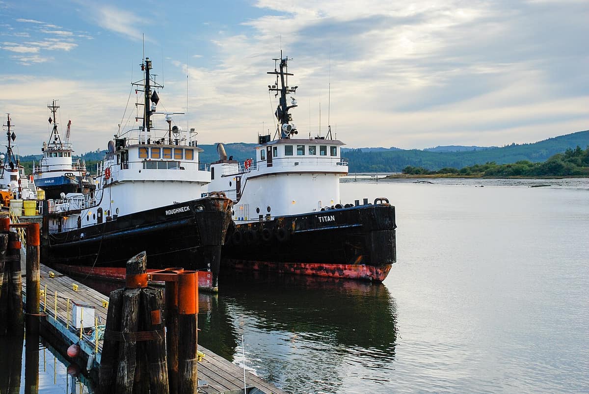 Two tugboats docked at a wooden pier on the Coos Bay waterfront