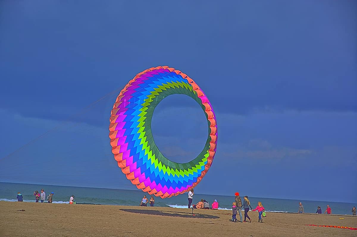 Giant rainbow ring kite spinning over the beach at the Lincoln City kite festival