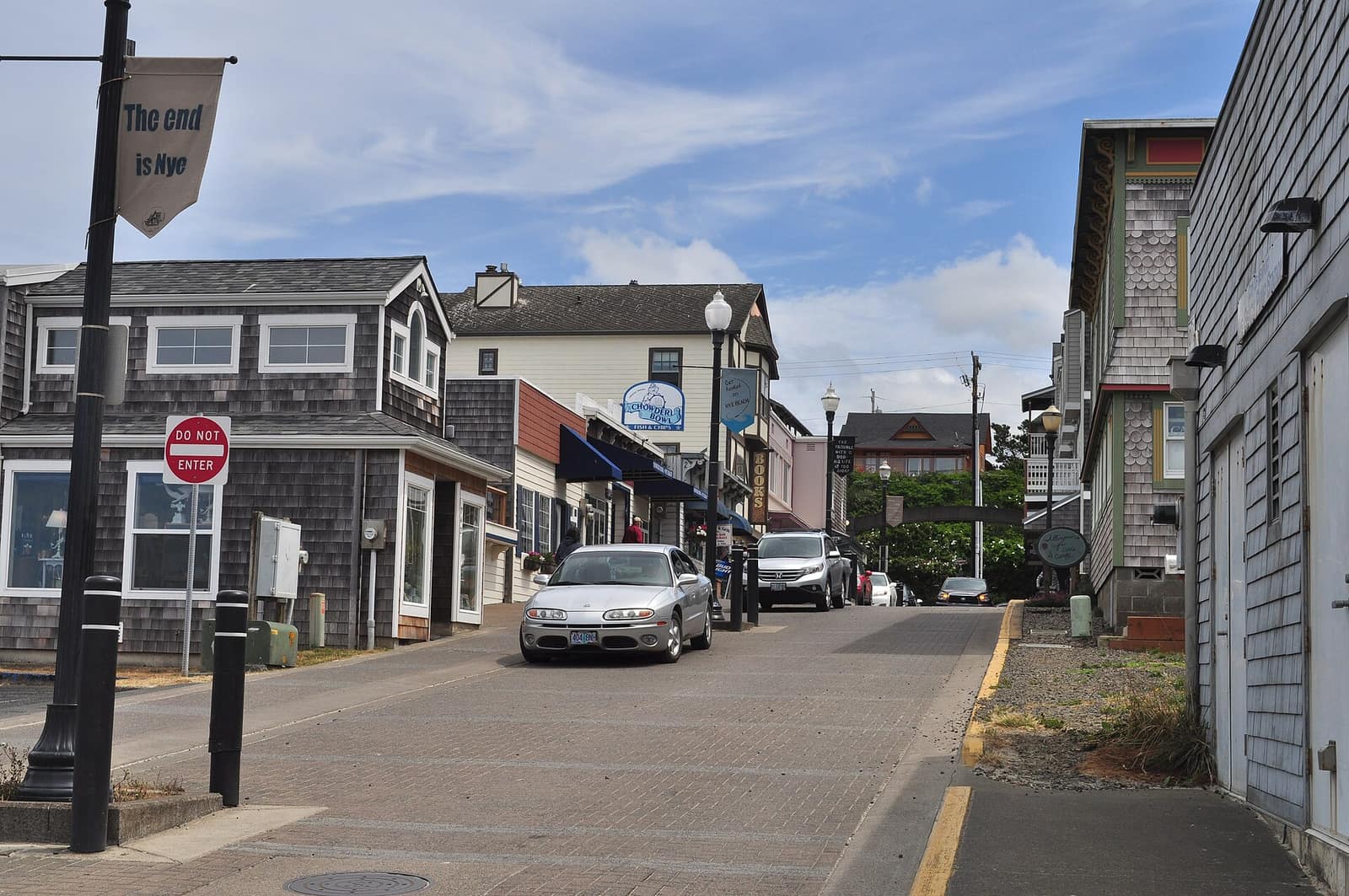A brick-paved street in the Nye Beach neighborhood of Newport, lined with shingled shops and cottages