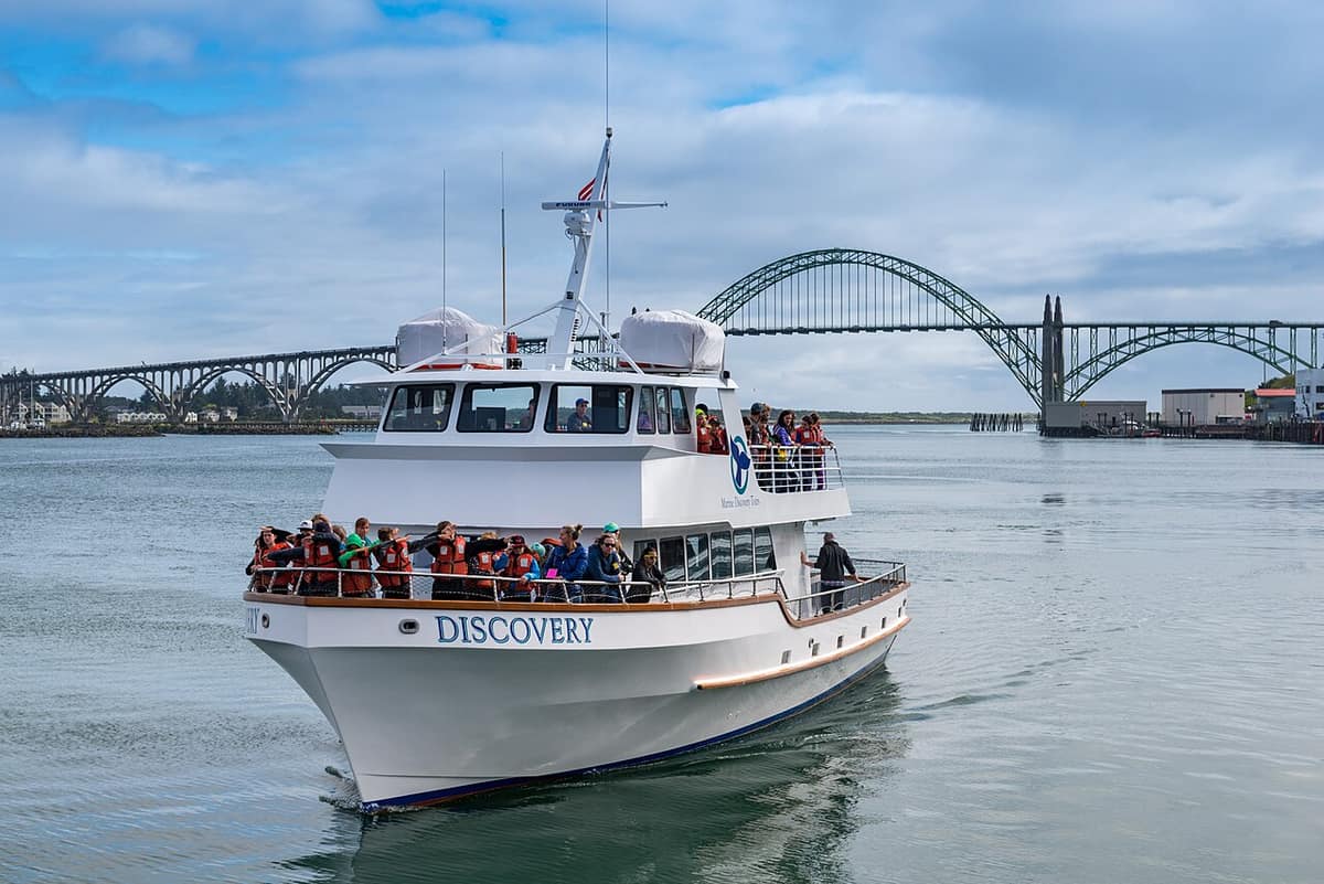 Tour boat on Yaquina Bay with the Yaquina Bay Bridge behind, seen from Newport's Bayfront